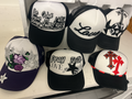 Peacefulcornerapparel collection of black and white trucker hats with faith-inspired embroidery and rhinestone motifs.